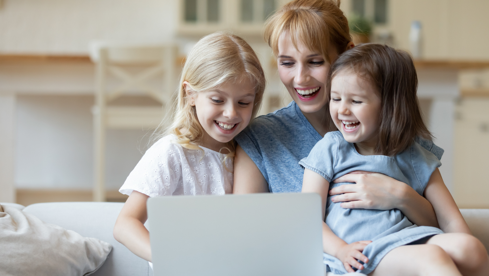 Mother and two daughters smiling at a laptop
